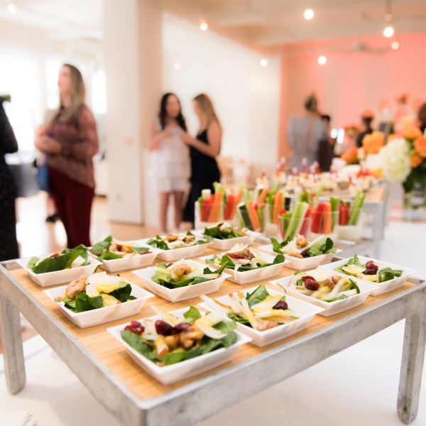 Buffet de salades et crudités lors d'un cocktail dînatoire élégant avec invités en arrière-plan.